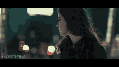 a woman in a black jacket is standing in front of a blurry city street at night .