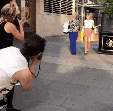 a woman taking a picture of another woman with a sign that says bee