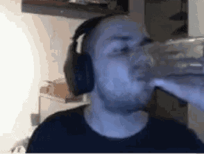 a man wearing headphones is drinking from a clear glass