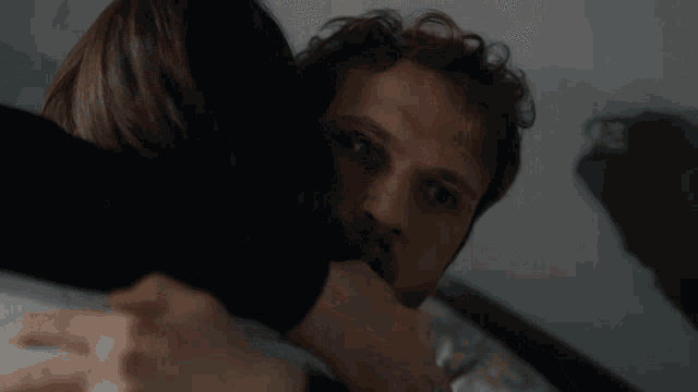 a man with a beard is hugging a woman with a ring on her finger