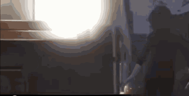a blurry picture of a person standing in front of a window with a light shining through it .