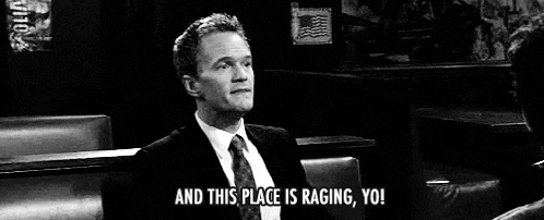 a man in a suit and tie is sitting on a couch in a bar .