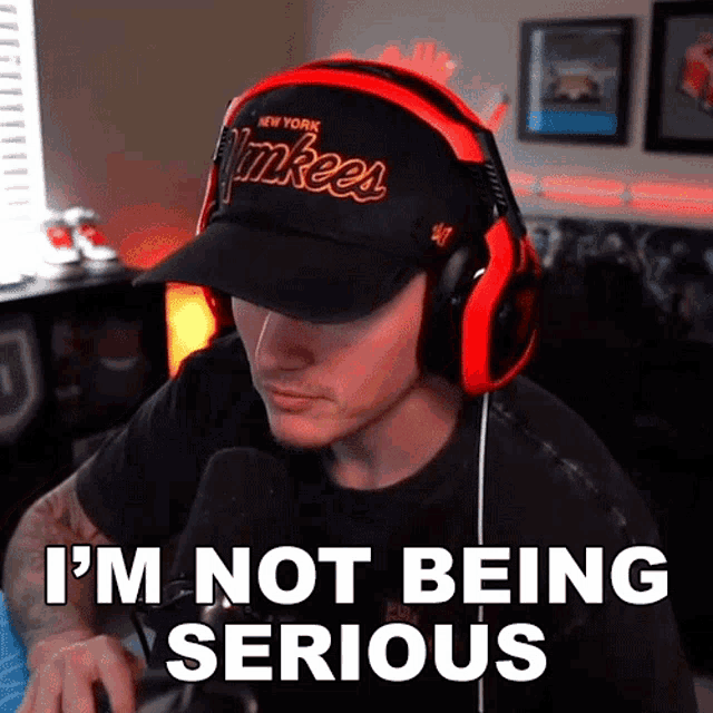 a man wearing headphones and a yankees hat is saying i 'm not being serious