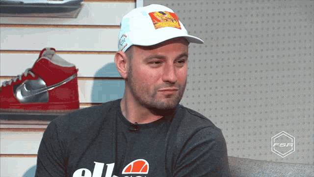 a man wearing a hat and a shirt that says ellesse on it