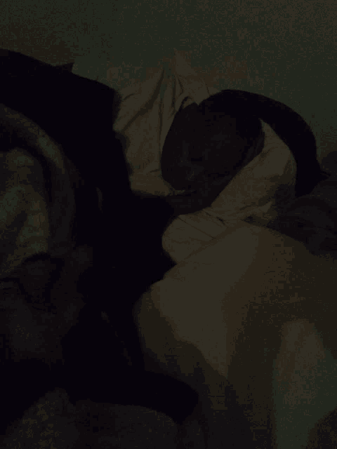 a person is sleeping in a dark room with a white blanket