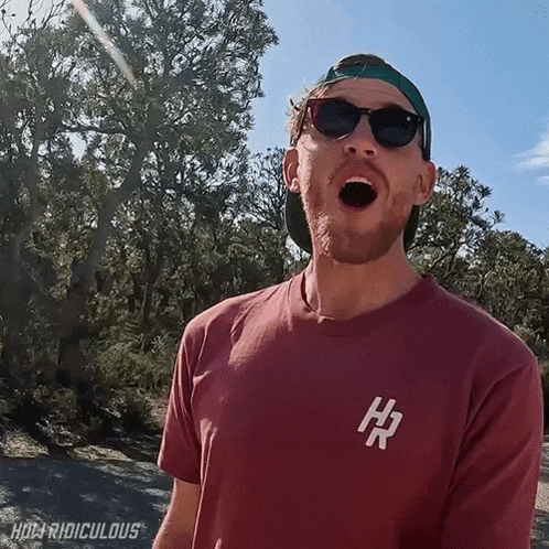 a man wearing sunglasses and a red t-shirt with the letter h on it