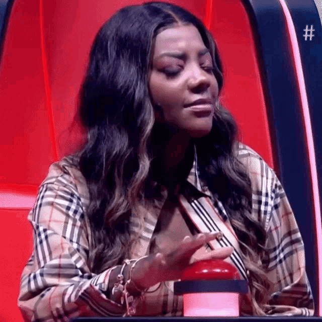 a woman in a plaid shirt is sitting in a red chair and pressing a button .