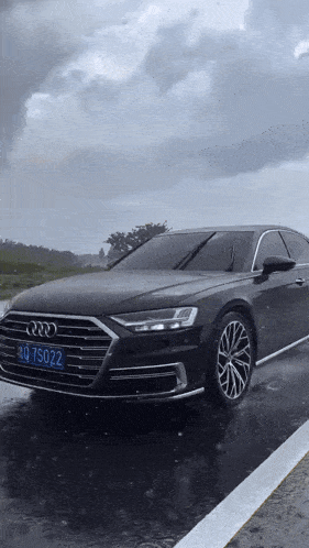 a black audi is parked in the rain with a license plate that says rq 75022