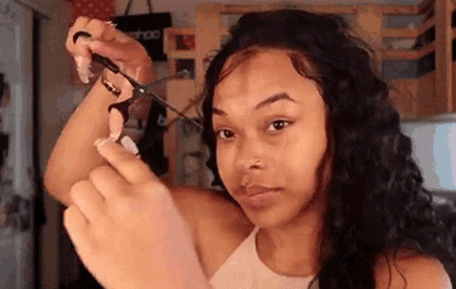 a young woman is cutting her hair with scissors .