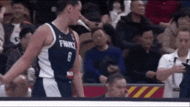 a basketball player with the number 6 on his jersey is standing in front of a crowd .