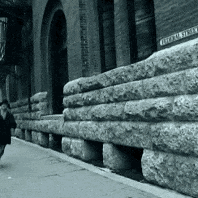 a black and white photo of a person walking down a street with a sign that says ' frederick st ' on it