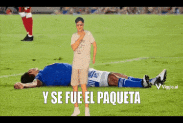 a man standing next to a soccer player laying on the field with the words y se fue el paqueta below