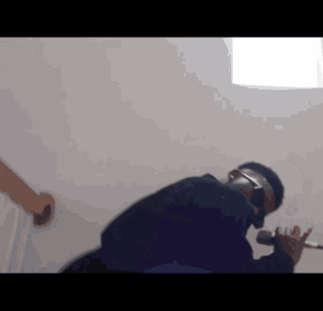a man wearing glasses and headphones is kneeling down in front of a wall