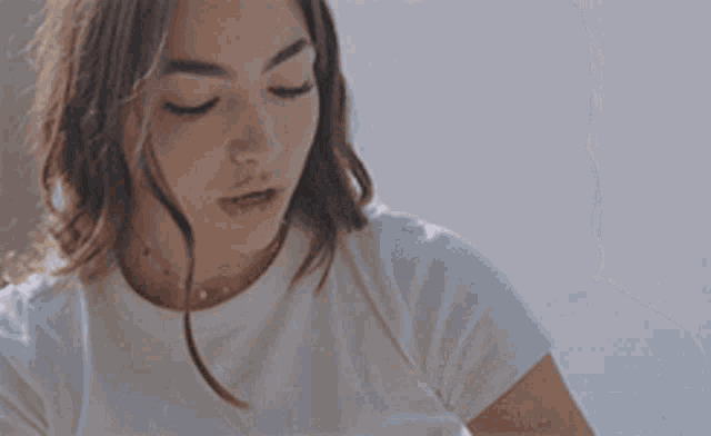 a woman is wearing a white t-shirt and a gold necklace
