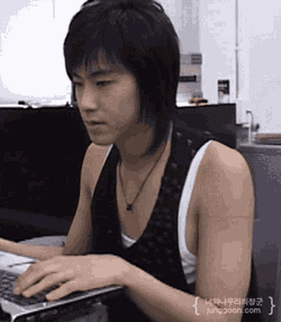 a young man is typing on a laptop with a picture of him taken by jungjoon.com