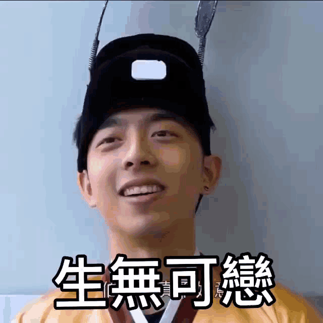 a young man wearing a hat with chinese writing on it is smiling .