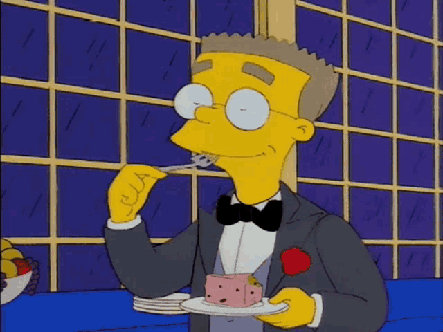 a man in a tuxedo is eating a piece of cake