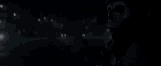 a man with a skull on his face is standing in the dark and talking .
