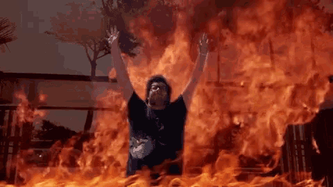 a man in a black shirt is surrounded by flames .