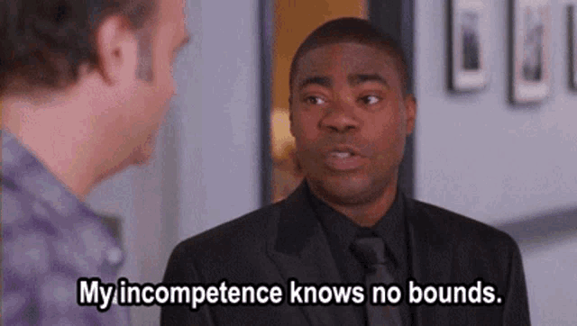 a man in a suit and tie is talking to another man and says " my incompetence knows no bounds "