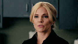 a woman with blonde hair is wearing earrings and a black jacket