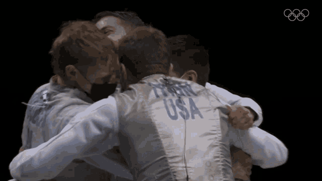 a group of men hugging each other one of whom is wearing a usa vest