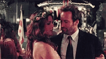 a man and a woman are dancing together in a bar . the woman has a flower crown on her head .