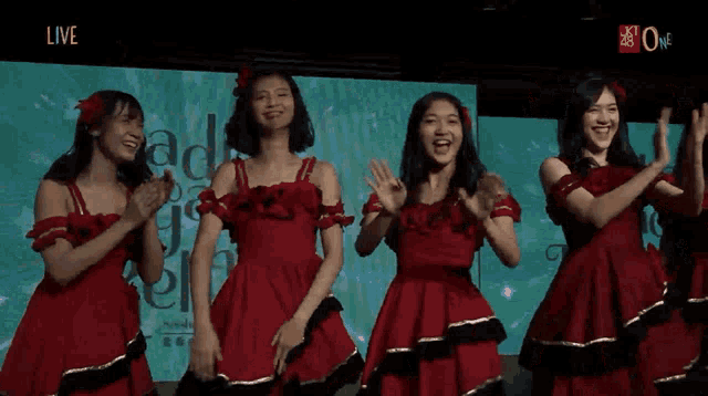 a group of girls are dancing in front of a screen that says live on it