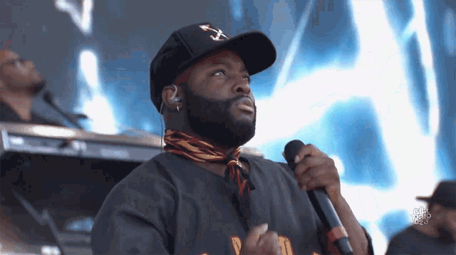 a man singing into a microphone while wearing a hat that says ' x ' on it