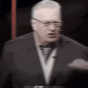 a blurry picture of a man in a suit and tie with glasses .