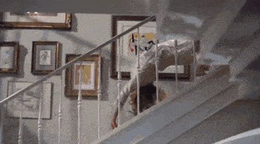 a person is crawling up a set of stairs in front of a wall of framed pictures