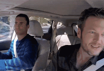 two men are sitting in the back seat of a car and smiling