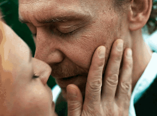 a close up of a woman kissing a man 's nose