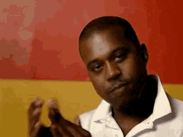 a man in a white shirt is clapping his hands in front of a red and yellow background .