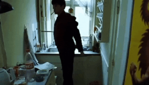 a man is standing in a kitchen with a coca cola bottle in the background .
