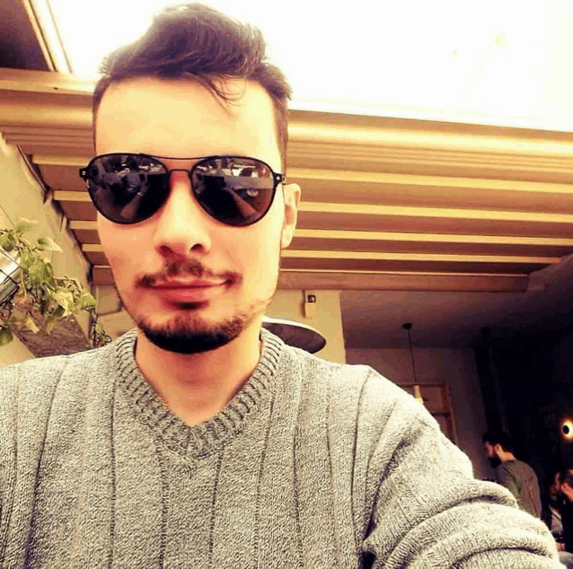 a man wearing sunglasses and a grey sweater