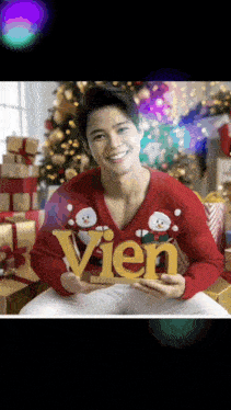 a man wearing a red sweater is holding a sign that says vien
