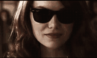 a close up of a woman wearing sunglasses and smiling at the camera .