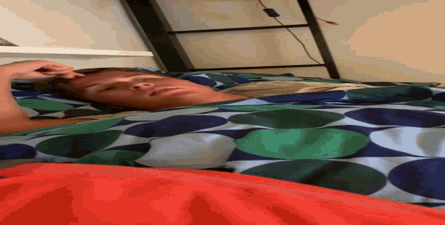 a man laying on a bed with a colorful blanket