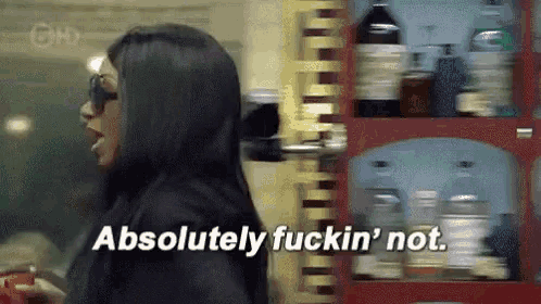 a woman is standing in front of a shelf with bottles and says `` absolutely fuckin ' not . ''