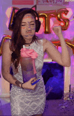 a woman wearing headphones and holding a water bottle with a sign that says " i want you " in the background
