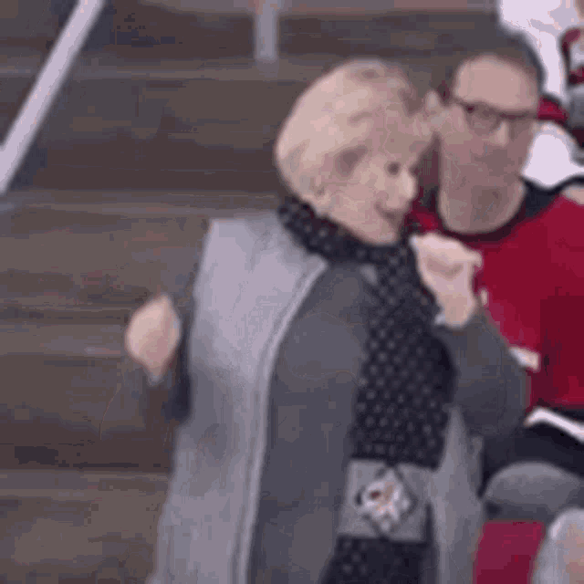 a woman is sitting in a stadium watching a hockey game and giving a fist bump .