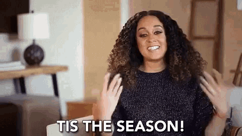 a woman with curly hair is sitting on a couch and smiling .