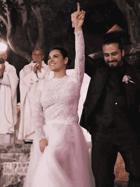a bride and groom are celebrating their wedding with a priest behind them