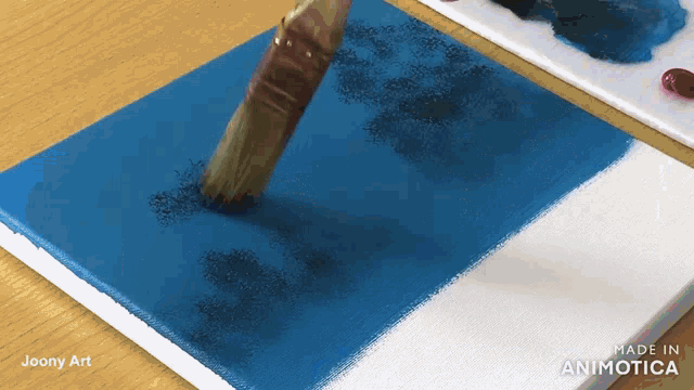a brush is being used to paint a blue and white canvas that is made in animatica
