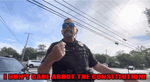 a police officer stands in front of a car with the words i don 't care about the constitution