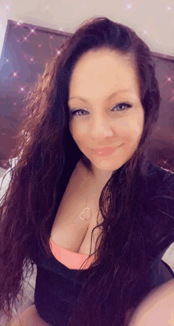 a woman taking a selfie with a heart necklace on her chest
