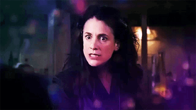a woman with long dark hair is making a funny face with her eyes closed