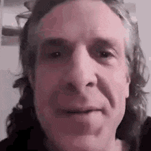 a man with long hair is making a funny face .