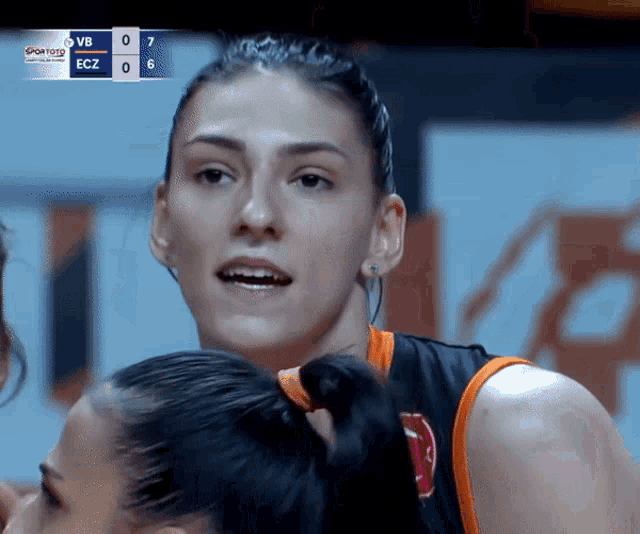 a female basketball player stands in front of a scoreboard which says ecz on it